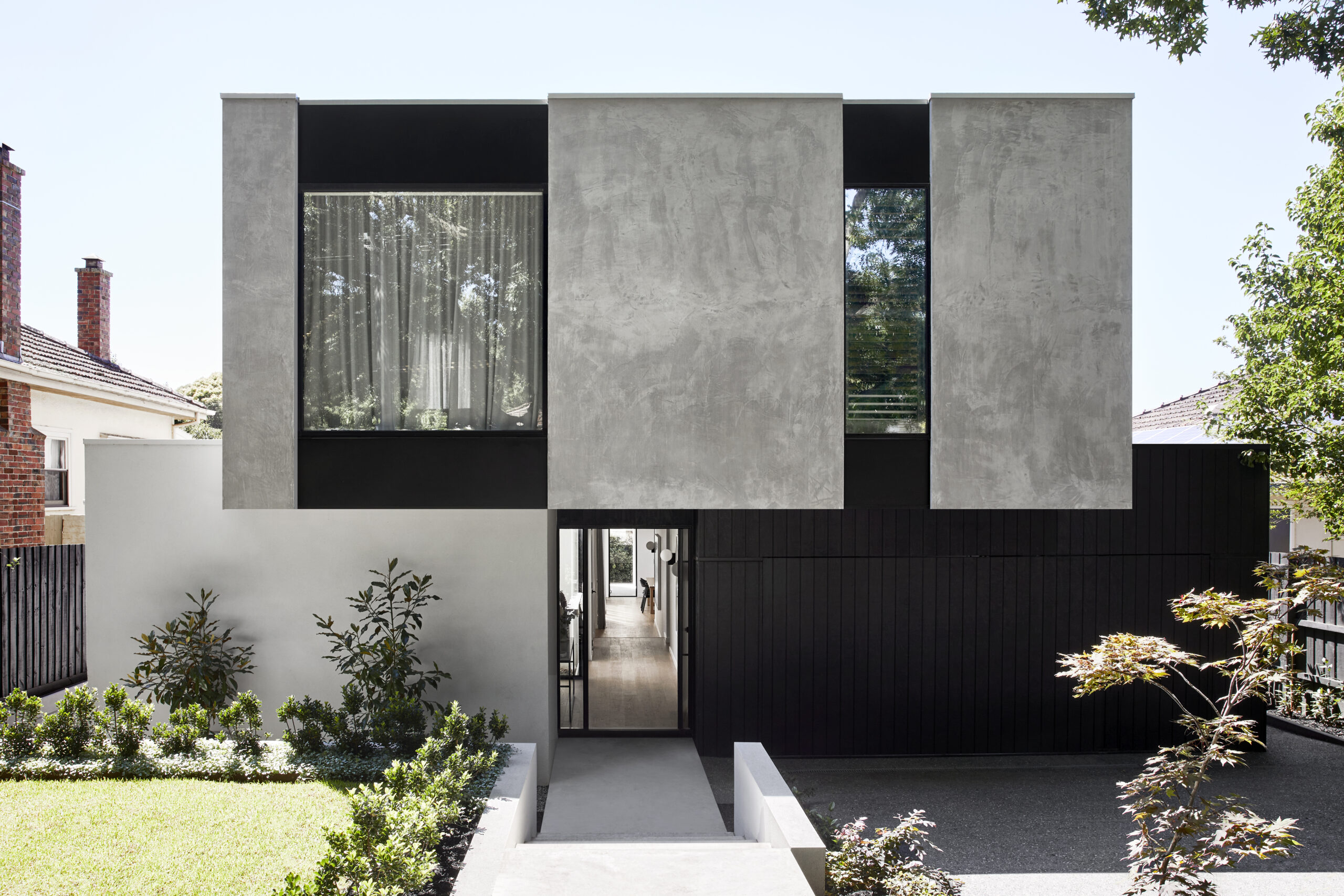 The façade of a double-storey home with grey, concrete-look Hebel and dark timber cladding.